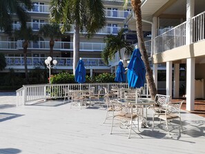 A rooftop patio with outdoor seating, white railings, and blue umbrellas.