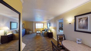 A hotel room with a zebra-striped carpet, a dining area with a round table, and a living area with a sofa and armchairs.