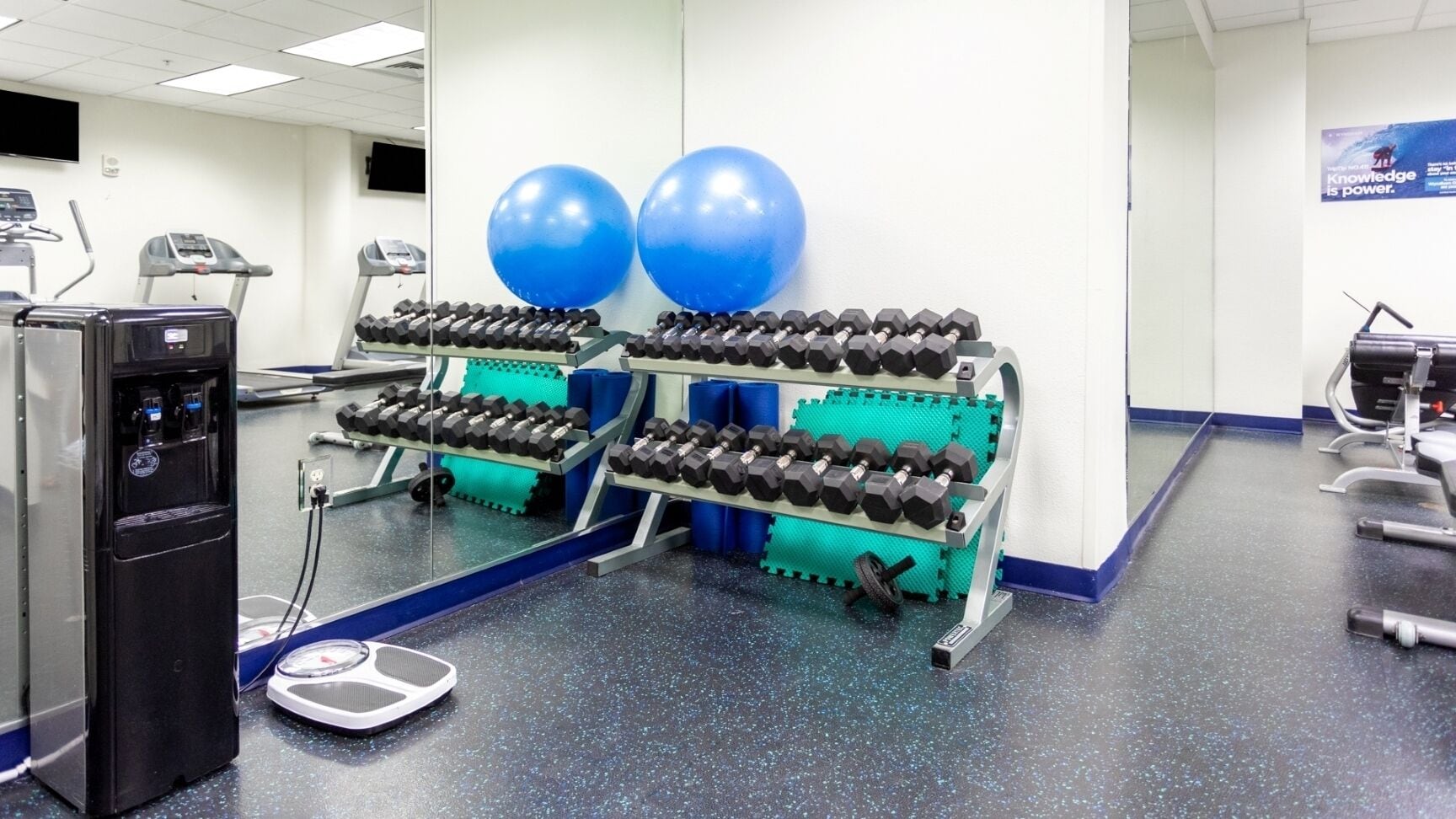 A gym with exercise equipment, a treadmill, and a scale.