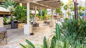 Eine Außenpatio-Terrasse mit Steinböden, Sitzgelegenheiten und verschiedenen Pflanzen.