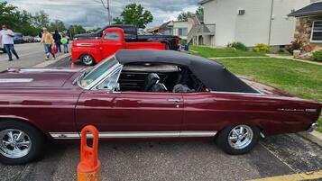 A classic maroon convertible car parked in a residential driveway.