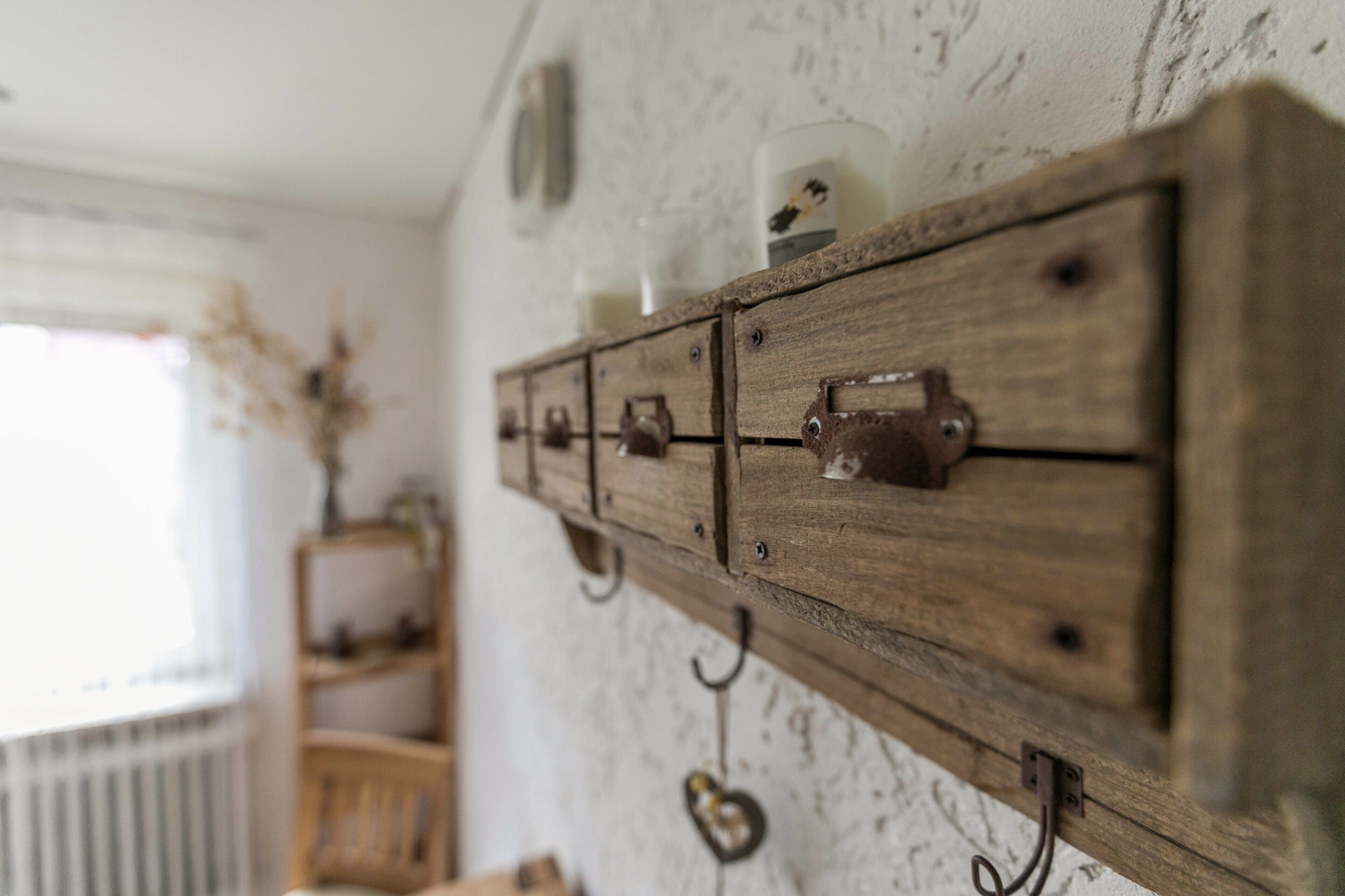 Un meuble en bois rustique, doté de nombreux tiroirs et de crochets, fixé à un mur à texture.