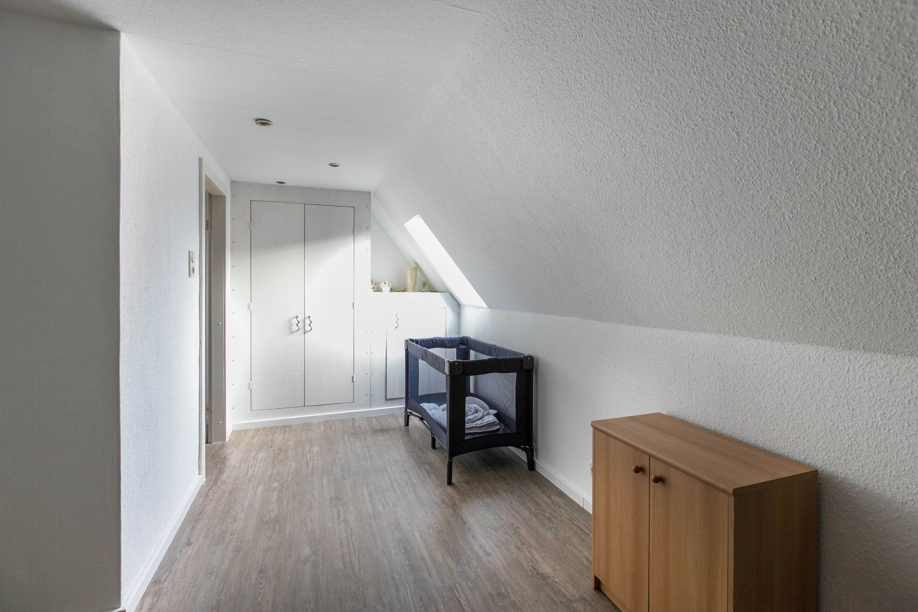 Ein Flur mit Holzboden, einem Etagenbett, einem Holzschrank und einer weißen Tür.