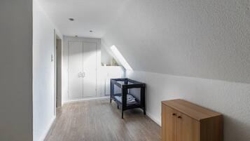 Ein Flur mit Holzboden, einem Etagenbett, einem Holzschrank und einer weißen Tür.