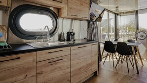 Een moderne keuken met houten kastjes, een zwart aanrecht en een raam. Er is een eethoek met een tafel en stoelen.