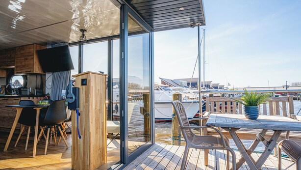 Een moderne camper met een keukenhoek, een eethoek en uitzicht op de jachthaven.