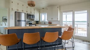 A modern kitchen with a large island, stainless steel appliances, and a view to the outside. - Private lagoon beach, Gulf beach steps away (Gulf Shores)