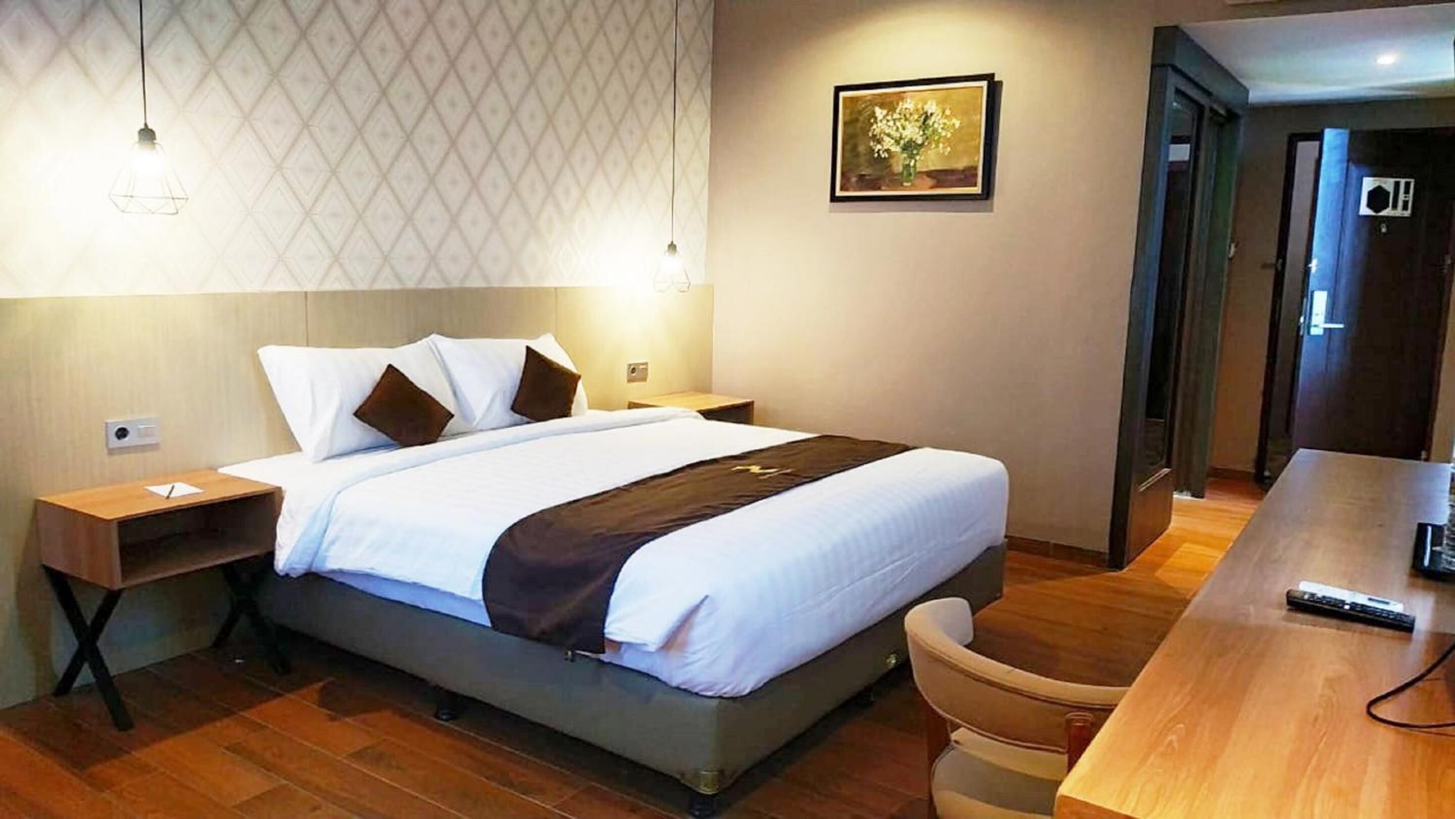 A hotel room with a bed, bedside tables, a desk, and a chair.