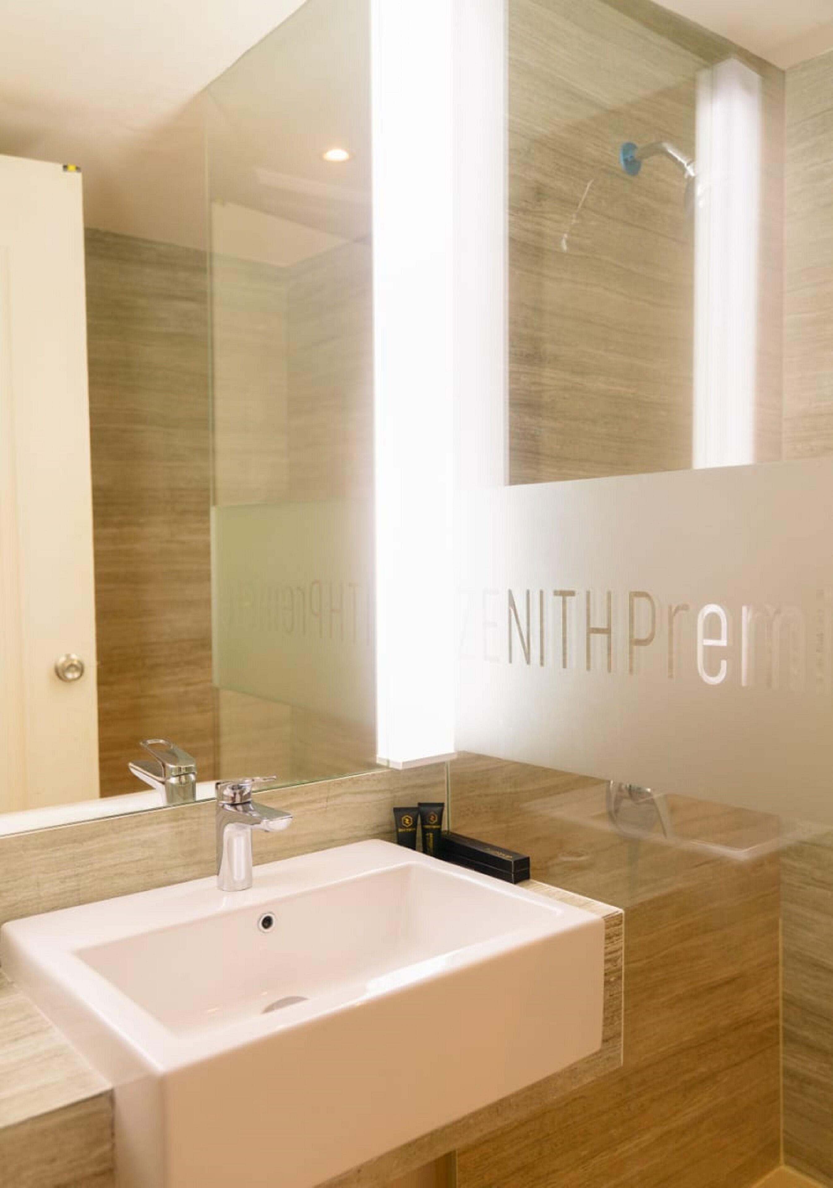 A modern bathroom with a large mirror, a sink, and a shower.