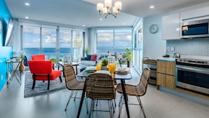 A modern kitchen with a large window, a dining area with wicker chairs, and a view of the sea.