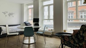 A modern, well-lit room with a large window, a desk with a computer, a sofa, and two chairs. - City Apartment in Copenhagen with 2 bedrooms sleeps 6 (Copenhagen)