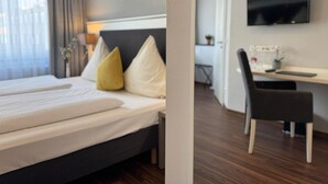 A hotel room with a bed, a desk, and a TV. - Mirage City Hotel Stuttgart (Stuttgart)