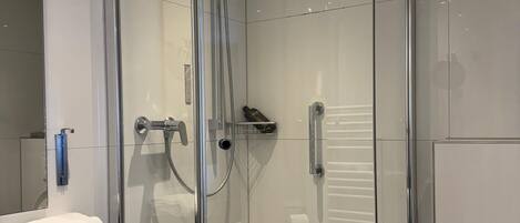 A modern bathroom with a glass-enclosed shower, a white sink with a black countertop, and a toilet.