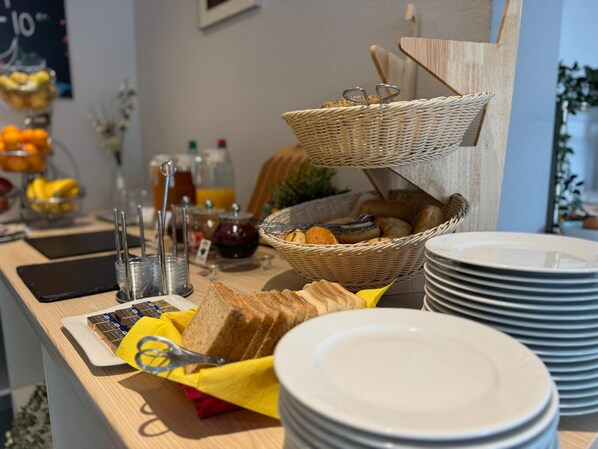 Una mesa de desayuno buffet con cestas de mimbre, platos y cubiertos.
