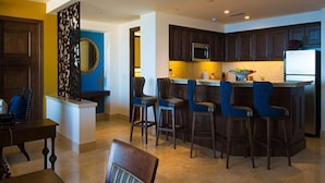A modern kitchen with dark wood cabinets, a central island with bar stools, and a microwave above the island. - 2Bedroom 3Bath Ocean Presidential Unit (Cabo San lucas)