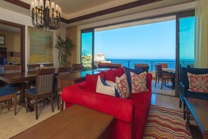 Ein geräumiges Wohnzimmer mit rotem Sofa, einem Essbereich und einem Balkon mit Meerblick.