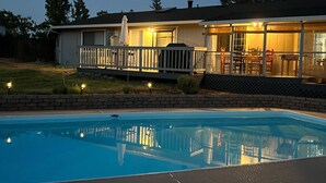 Um imóvel residencial com piscina, varanda coberta e área de deck cercada.