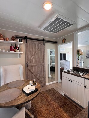 Une cuisine équipée d’une cuisinière à gaz, d’une table à manger en bois et d’une porte coulissante de style rustique.