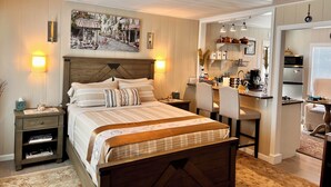 Une chambre confortable avec une tête de lit en bois, un lit avec une literie à rayures, des tables de chevet et un tableau accroché au mur.