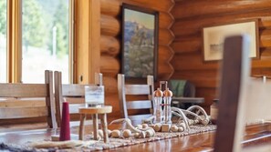 A wooden cabin interior with a dining table set for two, featuring salt and pepper shakers, a candle, and a woven placemat. - Last Resort (Red Lodge)