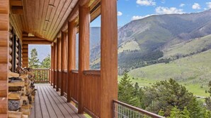 A wooden balcony with a view of a mountainous landscape. - Last Resort (Red Lodge)