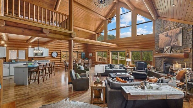 A spacious log cabin interior with a dining area, kitchen, and living room. - Last Resort (Red Lodge)