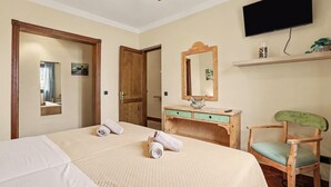 A hotel room with a bed, a wooden dresser, a chair, a television, and a mirror.