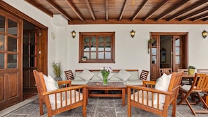 A wooden outdoor seating area with a table, chairs, and a window.