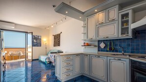 A kitchen with white cabinets, a blue tiled floor, a sink, and a stove. - Holiday Home "Pergola 714" Steps from the Beach with Sea View and Balcony (STINTINO)