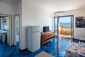 Quarto com cozinha, geladeira, televisão, armário de madeira e varanda com vista.