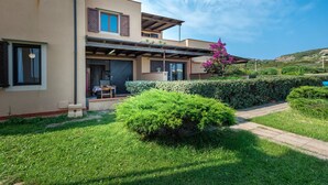 Une maison moderne à deux étages, dotée d’un patio couvert, d’un petit jardin et offrant une vue sur le paysage environnant.
