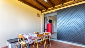 Un coin repas avec une table dressée pour quatre personnes, des chaises en bois, un réfrigérateur rouge et une porte coulissante.