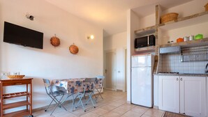 A compact kitchen with a dining area, a TV, and a microwave.