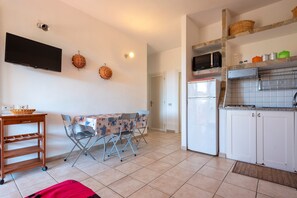 A compact kitchen with a dining area, a TV, and a microwave.