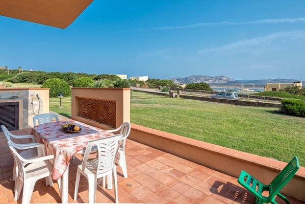 A patio with a table and chairs, a green chair, and a view of the landscape.