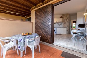 Un patio con mesa y sillas, una cocina al fondo y una puerta corrediza.