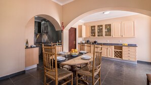 A kitchen with a dining table set for four, wooden chairs, a stove, and cabinets.