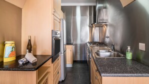 A modern kitchen with stainless steel appliances, a granite countertop, and wooden cabinets.