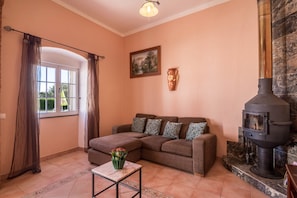 A living room with a sofa, a table with a vase, a fireplace, and a window with curtains. - Villa "Casa Santa Maria" with Pool, Wi-Fi, Terrace & Garden; Parking Available on Property (Boliqueime)