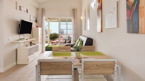 Een moderne woonkamer met een televisie, zithoek en kunstwerken aan de wanden.