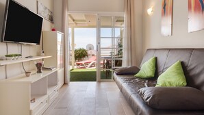 Een moderne woonkamer met een bank, televisie en een schuifdeur naar een buitenruimte.