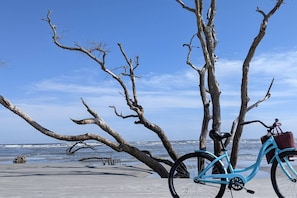Relax on the sandy shore, where a bicycle awaits, surrounded by the peaceful ocean views.