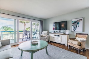 Relax in this stylish living room with a flat-screen TV, comfortable sofa, and wicker armchair.