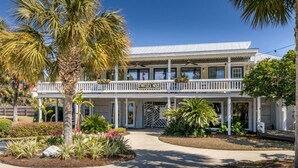 A two-story building with a balcony, surrounded by landscaped gardens and palm trees.