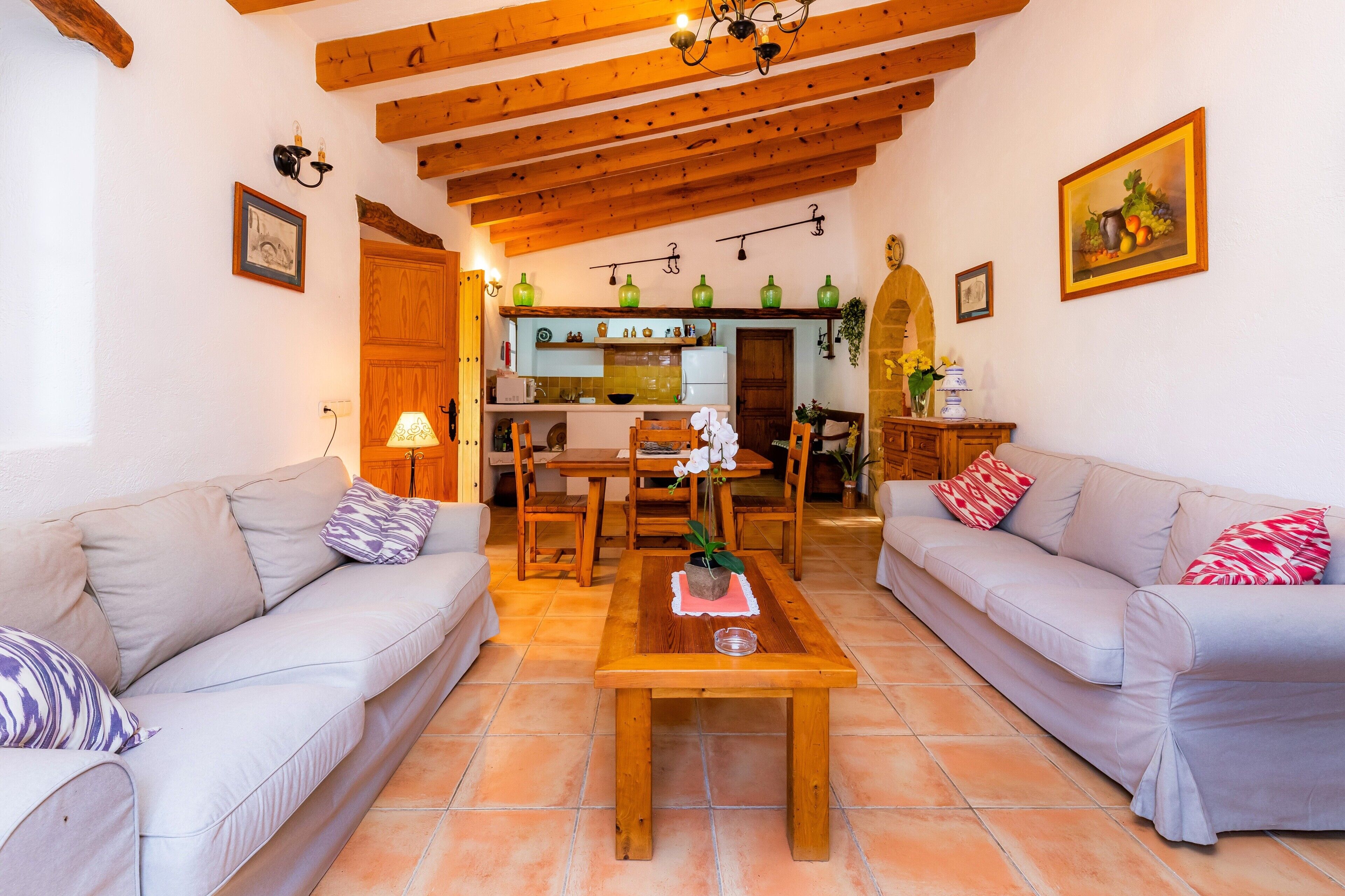 Una sala de estar con dos sofás, una mesa de centro de madera y una cocina al fondo.