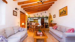 A living room with two sofas, a wooden coffee table, and a kitchen in the background. - Holiday Home 'Can Pedro Monjo' with Private Pool, Private Terrace and Wi-Fi (Alcudia)
