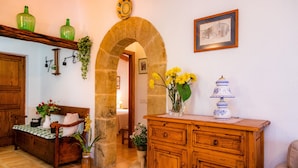 A cozy room with a wooden bench, a cabinet, a stone archway, and a vase with flowers. - Holiday Home 'Can Pedro Monjo' with Private Pool, Private Terrace and Wi-Fi (Alcudia)
