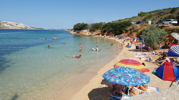 A beach with clear water, umbrellas, and people. - Sunset View Rab Apartment (Rab)