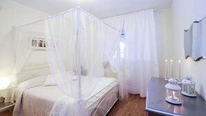 A bedroom with a four-poster bed, a bedside table with a lamp, and a nightstand.