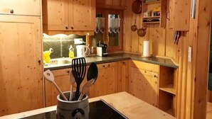 Puisesta materiaalista valmistettu keittiö, jossa on pesuallas, vedenkeitin ja erilaisia keittiövälineitä.